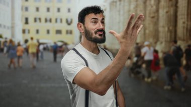 Bulanık insanlar ve tarihi mimari ile çevrili, eski Roma 'da neşeli jestler yapan İspanyol sakallı adam, canlı ve canlı bir şehir manzarası yaratıyor..