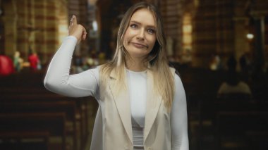 Kapalı mekanlarda el kol hareketi yapan bir kadın, kilise ortamında duygu gösteriyor, genç kişiliğini ve kültürel anını yakalıyor..