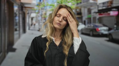 Bir sokak sahnesinde kadın, üniformalı, sarışın bir yargıcın dışarıda yorgun bir şekilde dikilirken stresli bir şekilde el ele tutuşuyor..