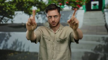 Sakallı genç adam, şehir sokaklarında yeşil çizgili parmakla 