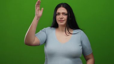 Artı mavi kazaklı kadın, izole edilmiş yeşil arka plana karşı hayal kırıklığı gösteriyor.