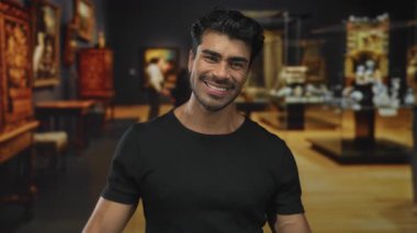 Erkekler sanat galerilerinde geniş bir gülümseme ile heykeller ve tablolar arasında kaya boynuzları hareketi yapar; sevinç kutlaması.