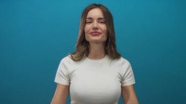 Latin kökenli genç bir kadın mavi stüdyoda alaycı bir ifadeyle hareketler sergiliyor. Şüphecilik iğneleme..