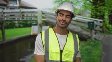 Kemerli ve güvenlik yeleği olan İspanyol genç adam bina girişinde el ile barış işareti gösterdi; iyimserlik umudu pozitifliği.