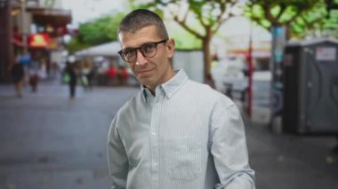 Açık havada gözlüklü ve çizgili tişörtlü bir adam meydan okuyor..