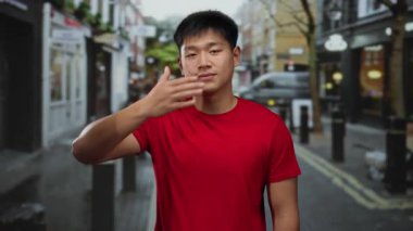 Kırmızı gömlekli genç adam şehir caddesinde bir şehir manzarasını neşe içinde resmediyor..