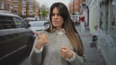 Bulanık şehir arka planı ve sonbahar ortamına sahip, konsantrasyon ve günlük tarzıyla hareketli bir caddede dikilen İspanyol kadın parmaklarını sayıyor..