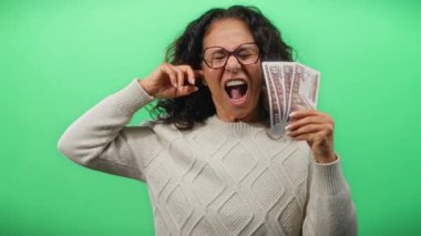 Yeşil arka planda Mısır banknotları tutan kadın orta yaşlı yüz ifadesi sergiliyor..