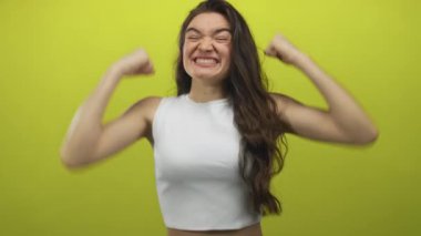 Uzun siyah saçlı, geniş sırıtışlı ve parlak yeşil stüdyo duvarına karşı yumruklarını sıkan bir kadın. Heyecan..