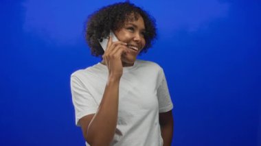 Stüdyoda kadın doğal olarak gülümsüyor ve akıllı telefonu kulağına tutuyor; olumlu diyalog bağlantısı iyimserliği.