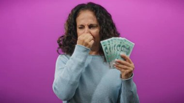 Mor duvara karşı iğrenç bir ifadeyle Çin yuanı tutan kadın, parayla ilgili kötü bir koku olduğunu ima ediyor..