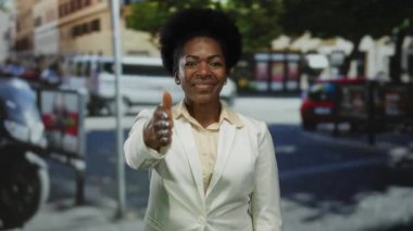 Meşgul şehir caddesinde, arka planda açık hava ışığı altında arabalarla selamlaşmak için elini uzatan kadın