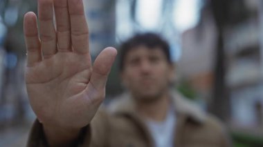 Bir sokakta durup, şehir atmosferini yakalayan İspanyol bir adam şehrin bulanık arka planına ve palmiye ağaçlarına karşı uzanmış ellere odaklanıyor..