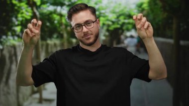 Sakallı genç bir adam arka planda ağaçlarla dolu bir şehir sokağında huzur belirtileri gösteriyor. Rahat ve rahat bir şehir havasını somutlaştırıyor..