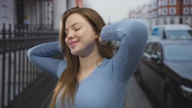 Kadın demiryolu ile meşgul şehir caddesinde kollarını açıyor ve arkasında park etmiş arabalar, başını arkaya yaslıyor; özgürlük.