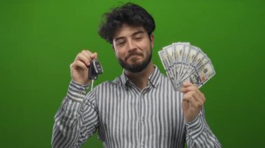 Sakallı genç adam arabanın anahtarlarını tutuyor ve biz dolarları yeşil bir geçmişe karşı, gülümsüyor ve zenginlik ve başarı sergiliyor..