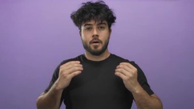 Genç sakallı, gözleri kapalı, canlı mor bir arka plana karşı meditasyon pozu veren sakin ve konsantre bir adam.