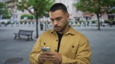 Kahverengi ceketli bir adam hareketli şehir caddesinde çıplak elle akıllı telefon tutuyor. Dijital merak..