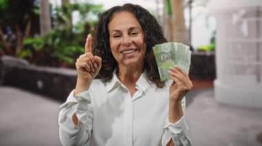 Bir şehir caddesinde elinde Şili banknotları tutan bir kadın, düşünceli ve bir fikri olan, canlı bir şehir ortamının ortasında pezoları ve finansal kavramları sergiliyor.