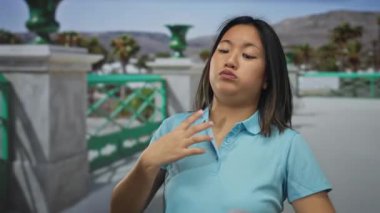 Güneşli bir sokakta tasmayı ayarlayan bir kadın canlı şehir manzarasında açık bir günde neşeli bir ifade ve günlük kıyafetle şehir atmosferini yakalıyor.