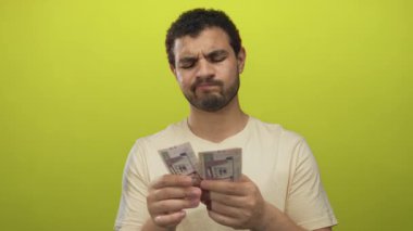 Genç İspanyol adam limon yeşili stüdyo duvarına karşı Suudi riyal faturalarını dikkatlice sayıyor..