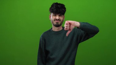 İzole edilmiş bir ortamda yeşil duvara karşı baş aşağı bir jest yaparak hoşnutsuzluğunu ifade eden adam, açıkça tasvip etmiyordu..