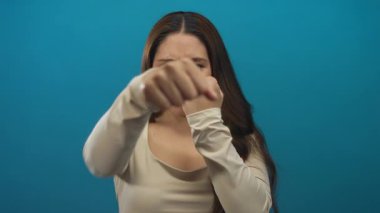 Mavi stüdyoda enerjik odaklı gülümseyen yumruk; dayanıklılık ve kendine güven güçlendirme.