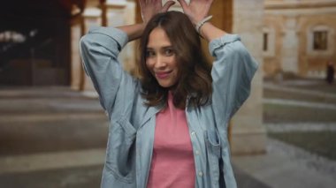 Eski bir üniversite binasında neşeli jestler yapan bir kadın gençlik ruhunu ve İspanyol mirasını tarihsel bir zemine karşı sergiliyor..