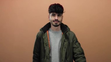 Yeşil ceketli genç adam kahverengi arka planda şef öpücüğü veriyor izole edilmiş portre tarzı.