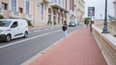 Bulanık kadın, arka planda şehir manzarası ve mimarisini ön plana çıkaran bokeh efektiyle lüks Monako caddesinde yürüyor.