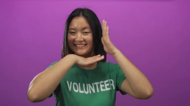 Gülümseyen ve el hareketleri yapan bir kadın yeşil gönüllü tişörtü giyen canlı pembe arka plan kapalı alanda izole edilmiş mutlu yüz ifadesi..