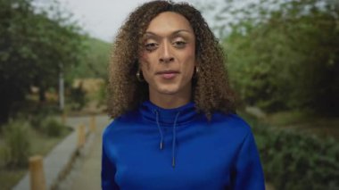 Ağzı ve eli açık bir kadın ormandaki yeşil yaprakların arasında kirli bir patika boyunca yan tarafı işaret ediyor; merak..