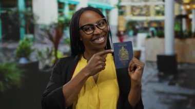 Şehirde elinde Kanada pasaportuyla gezen bir kadın. Gözlüklü ve sarı gömlekli bir kadın. Şehir içi seyahat onayına karşı gülümsüyor..