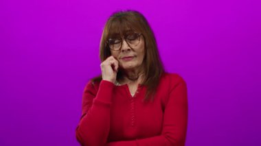 Gözlüklü, kırmızı süveter giyen, yüzünde pembe izole bir arka plan olan İspanyol bir kadın..