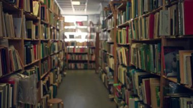 Kitaplarla dolu kütüphane koridoru, uzak uçtaki pencereden süzülen güneş ışığı gibi kapalı alanda okumak ve çalışmak için rahat ve sessiz bir atmosfer yaratıyor..