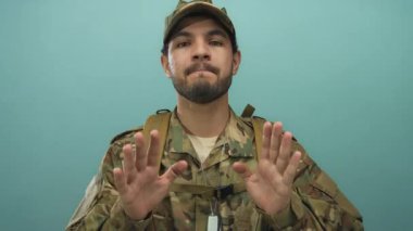 Stüdyoda kamuflaj üniforması giyen genç İspanyol asker ve avuçlarını kaldırmış künye takıyor..