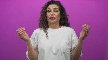 Pembe stüdyoda beyaz gömlek giyerken avuçlarıyla omuz silken İspanyol bir kadın; belirsizlik..