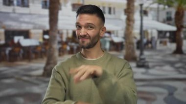 Genç İspanyol asıllı adam dışarıda el kol hareketi yapıyor. Hayır, parmaklarıyla çapraz kollar yapıyor. Şehir sokaklarında reddediliyor.