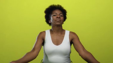 Huzurlu bir şekilde kollarını öne doğru uzatan kadın izole edilmiş sarı arka planda sakin ve bilinçli olduğunu ifade ediyor..