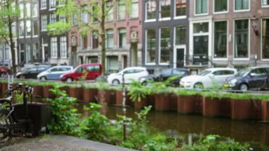 Bisikletler, arabalar ve geleneksel mimariyle Amsterdam Kanalı 'nın bulanık görüntüsü şehrin şehir cazibesini ve hareketli sokak manzarasını yansıtıyor..