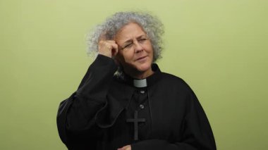 Dini giyinmiş yaşlı gri saçlı kadın, ilham ve bilgeliği ifade eden sarı arkaplana karşı fikir beyan eder..