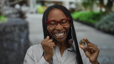 Elinde Monero sikkesi tutan gülümseyen bir kadın. Şehir sokaklarında kripto para ve engelleme teknolojisi hakkında heyecan sergiliyor..