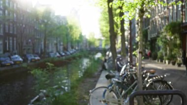 Parlak gün ışığı altında bisiklet, ağaç ve tarihi binalarla bulanık amfi kanal sahnesi huzur verici titreşimler sunuyor.