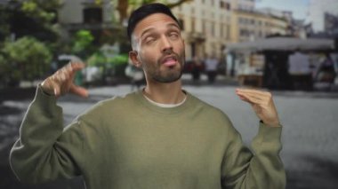 İspanyol asıllı genç adam şehir sokaklarında hareketli hareketler yapıyor. Arka planda insanlar ve binalar var. Canlı bir şehirde ifade ve duygu aktarıyor..