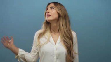 Beyaz gömlekli, dalgalı saçlı bir kadın fotoğraf stüdyosunda göz devirme hareketi yapıyor..