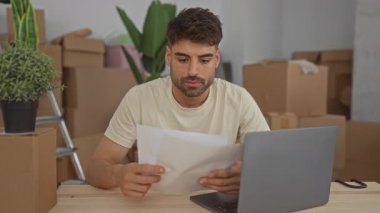 Binanın içindeki karton kutuların arasında dizüstü bilgisayarın yanındaki ahşap masada oturan adam, heyecan.