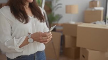 Kutular ve bitkilerle çevrili yeni bir evde dolarlar tutan İspanyol kadın başarılı bir hareketi ya da yeni bir başlangıcı simgeliyor..