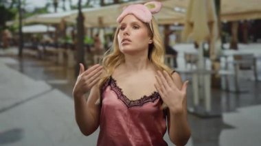 Göz maskeli pembe gecelikli kadın gündüzleri şehir caddesinde dikiliyor..