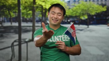 Kentsel caddede elinde Hırvat bayrağı olan Asyalı bir adam ulusal gurur ve gönüllü ruhu açık şehir ortamında sergiliyor..