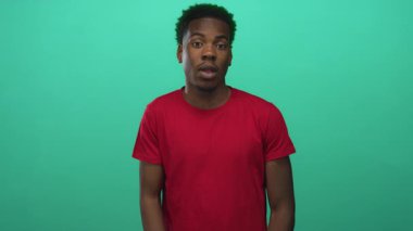 Yeşil stüdyoda ani ağrı gösteren ağzı açık kırmızı gömlek debriyajlı bir adam..